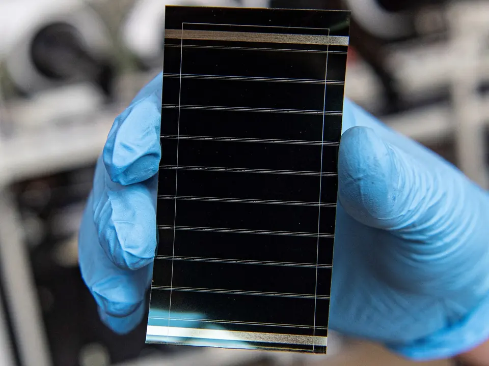 Gloved hands holding a printed perovskite solar module