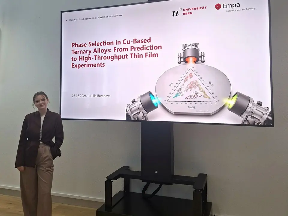 Iuliia Baranova beside the title slide of her Master’s thesis defense